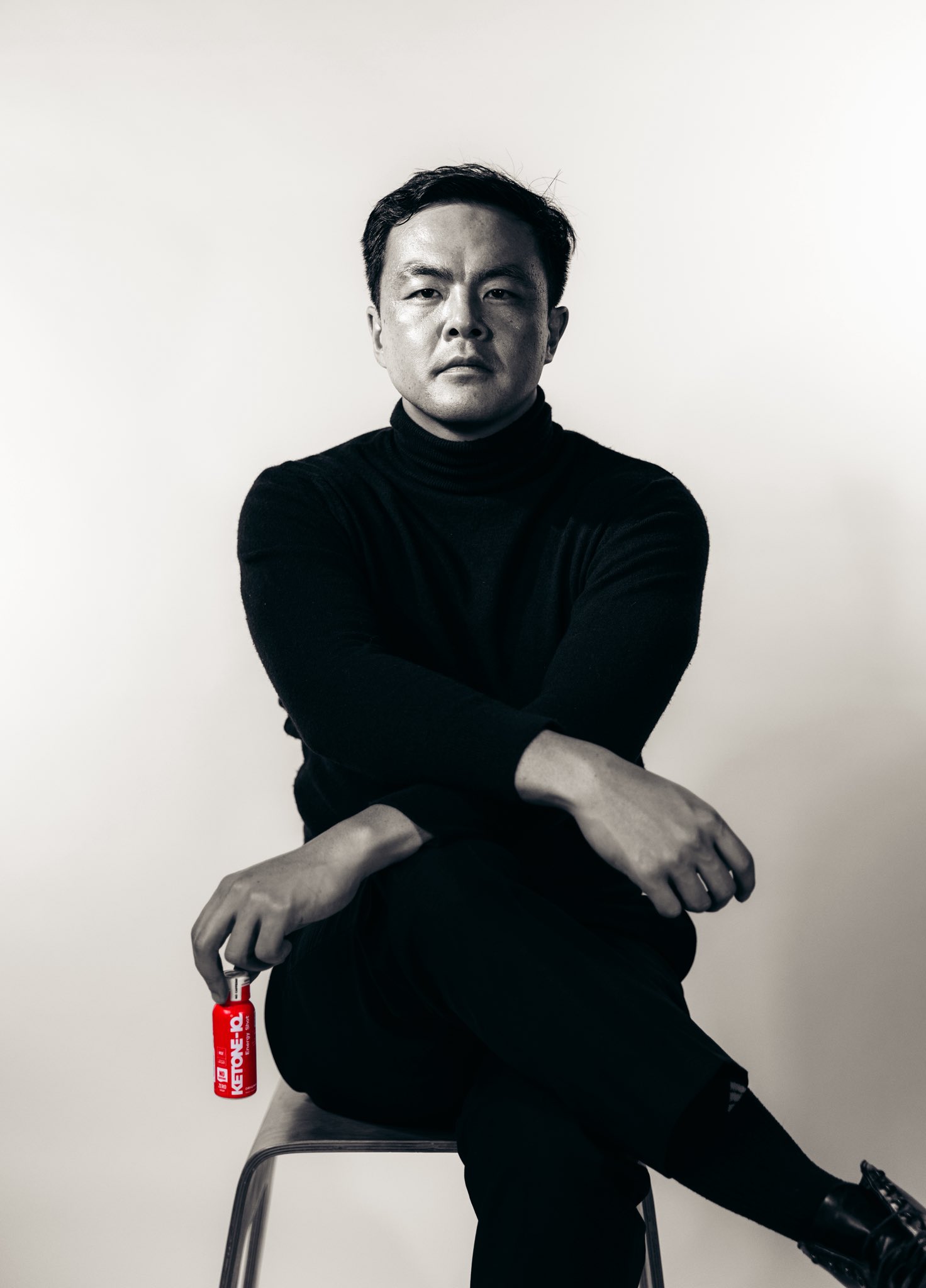 Geoff Woo seated in a black turtleneck holding a Ketone-IQ shot